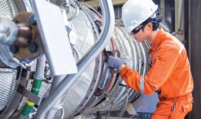 A man in an orange uniform working on a large machine